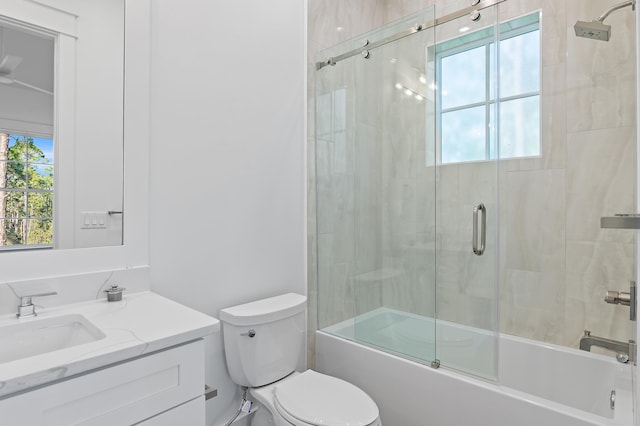 full bathroom with combined bath / shower with glass door, vanity, toilet, and a healthy amount of sunlight