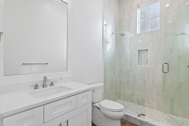 bathroom featuring a shower with door, vanity, hardwood / wood-style floors, and toilet