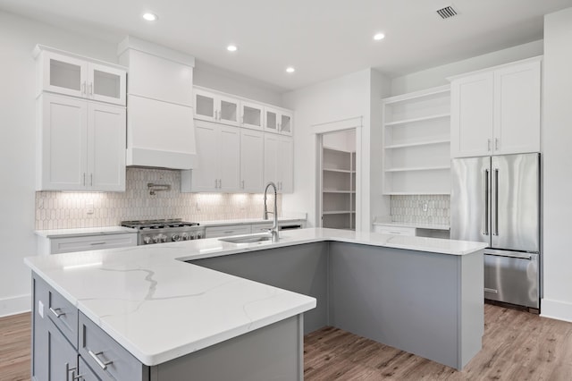 kitchen featuring sink, stainless steel appliances, light hardwood / wood-style floors, a center island with sink, and white cabinets