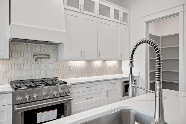 kitchen featuring white cabinets, decorative backsplash, and stainless steel range