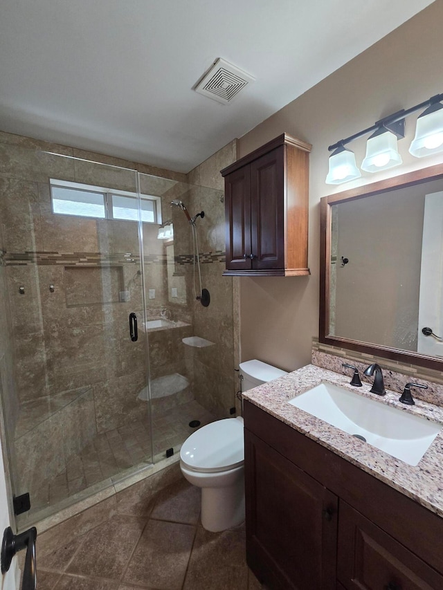 bathroom featuring tile patterned flooring, vanity, toilet, and a shower with door