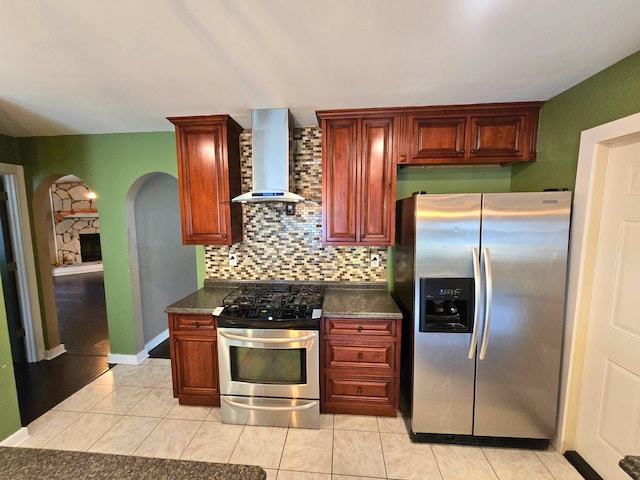 kitchen featuring appliances with stainless steel finishes, backsplash, light tile patterned floors, and wall chimney exhaust hood