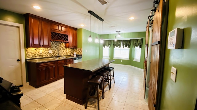 kitchen with sink, hanging light fixtures, backsplash, a breakfast bar, and a kitchen island