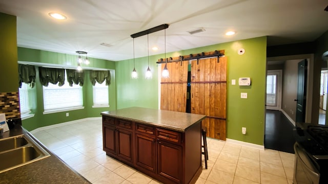 kitchen featuring a center island, sink, hanging light fixtures, a kitchen bar, and light tile patterned floors