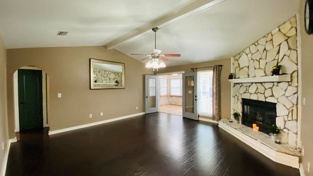 unfurnished living room featuring ceiling fan, french doors, vaulted ceiling with beams, a stone fireplace, and dark hardwood / wood-style floors