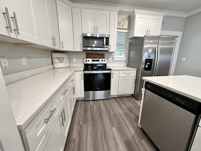 kitchen with crown molding, appliances with stainless steel finishes, light stone countertops, white cabinets, and light wood-type flooring