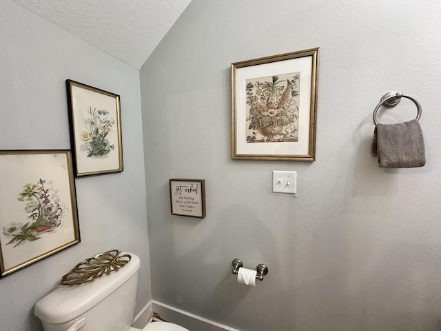 bathroom with lofted ceiling, a textured ceiling, and toilet