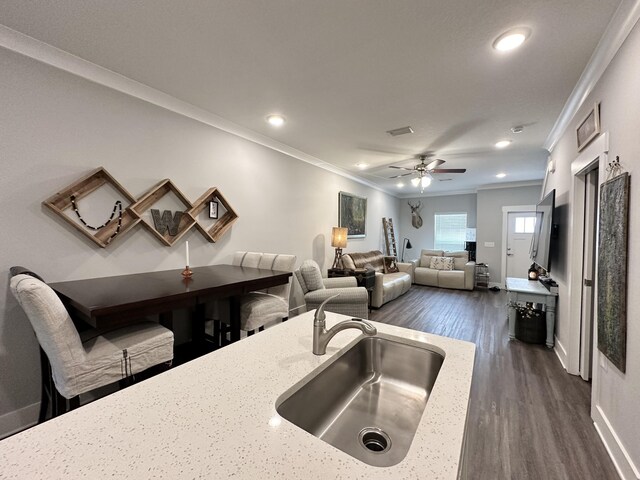 kitchen featuring sink, ceiling fan, ornamental molding, dark hardwood / wood-style flooring, and light stone counters