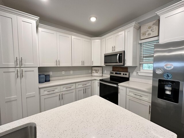 kitchen featuring light stone counters, white cabinets, and stainless steel appliances