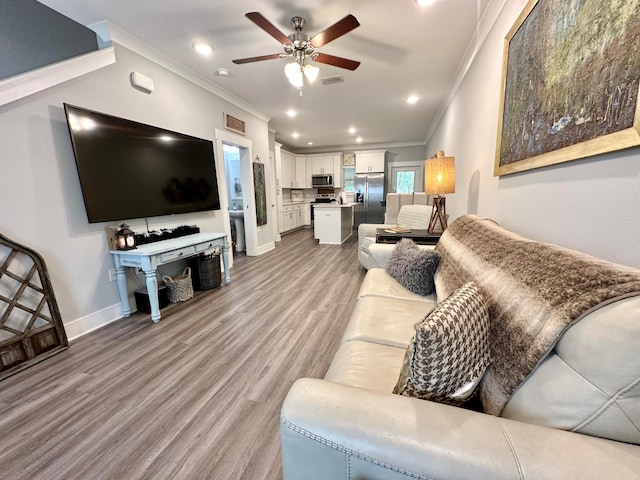 living room with crown molding, ceiling fan, and light wood-type flooring