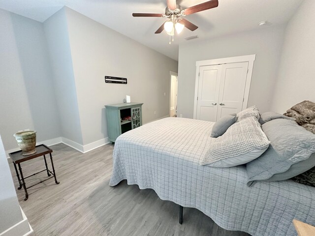 bedroom with a closet, hardwood / wood-style flooring, and ceiling fan