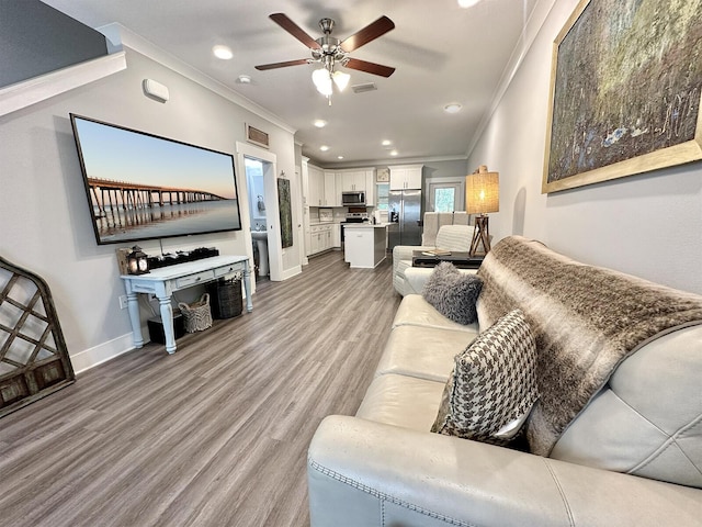 living room with light hardwood / wood-style flooring, ornamental molding, and ceiling fan