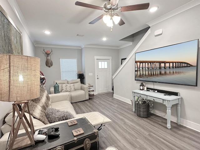 living room with wood-type flooring, ornamental molding, and ceiling fan