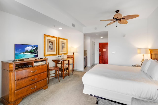 bedroom with ceiling fan, light colored carpet, and connected bathroom