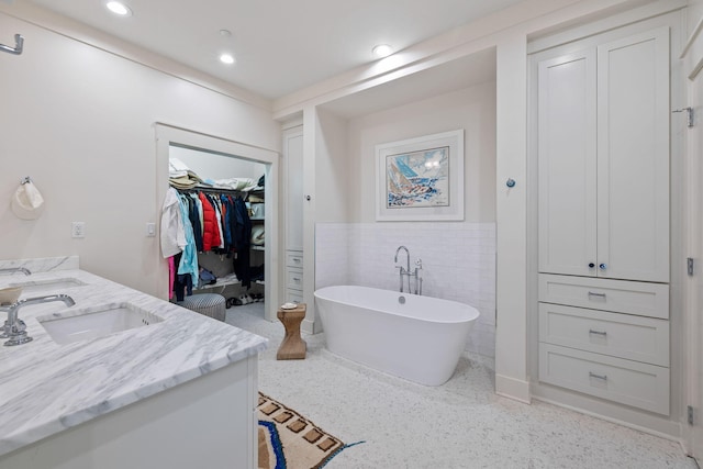 37 S Compass Point Way Unit 107, Inlet Beach, FL 32461 - full bathroom featuring double vanity, a soaking tub, wainscoting, tile walls, and speckled floor
