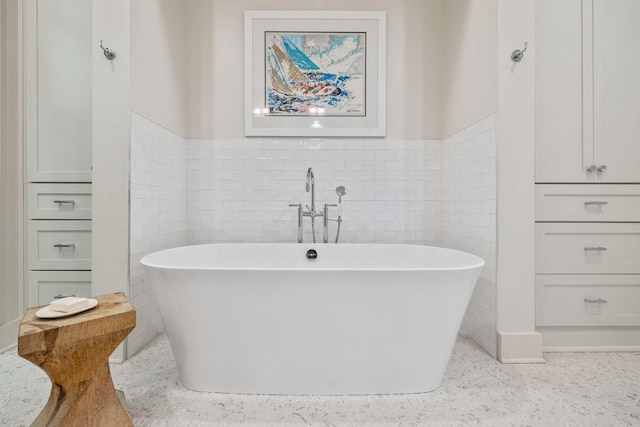 full bathroom with a soaking tub, tile walls, and a wainscoted wall