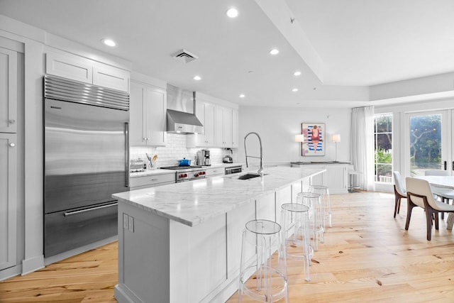 37 S Compass Point Way Unit 107, Inlet Beach, FL 32461 - kitchen featuring premium appliances, a center island with sink, recessed lighting, light stone counters, and light wood finished floors