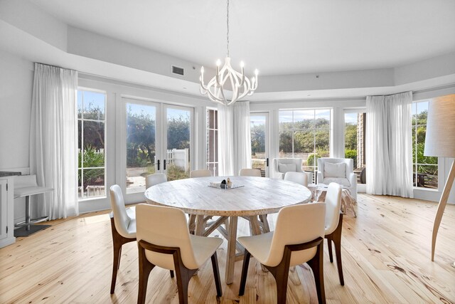 dining space with light wood-style flooring, a notable chandelier, french doors, and visible vents