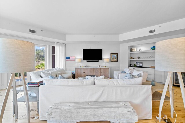 living area with visible vents, light wood-style flooring, and built in features