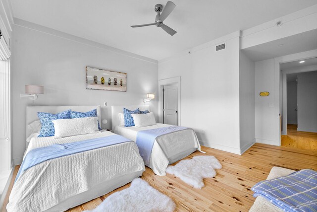 bedroom featuring ceiling fan, visible vents, baseboards, and wood finished floors