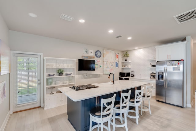 168 Secret St, Freeport, FL 32439 - kitchen featuring stainless steel fridge, open shelves, a kitchen island with sink, white cabinets, and black electric stovetop