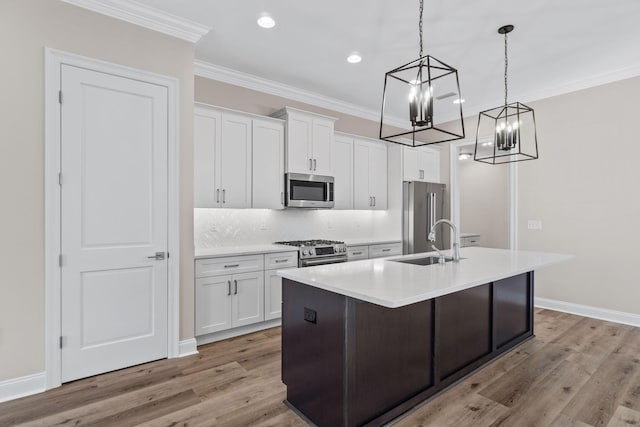 kitchen with white cabinets, decorative light fixtures, an island with sink, and appliances with stainless steel finishes