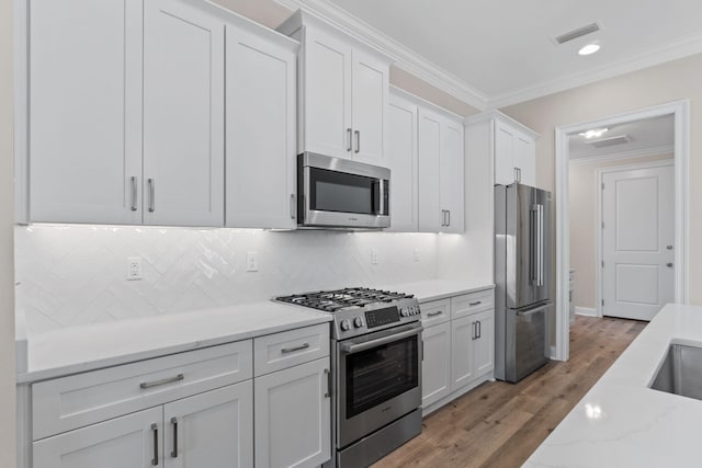 kitchen with crown molding, tasteful backsplash, light stone counters, white cabinetry, and stainless steel appliances