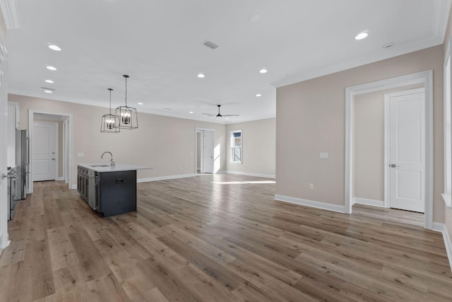 kitchen featuring a center island with sink, ceiling fan, hanging light fixtures, and light hardwood / wood-style flooring