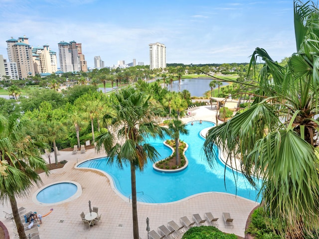 view of pool featuring a water view, a hot tub, and a patio