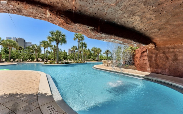 view of swimming pool with pool water feature and a patio