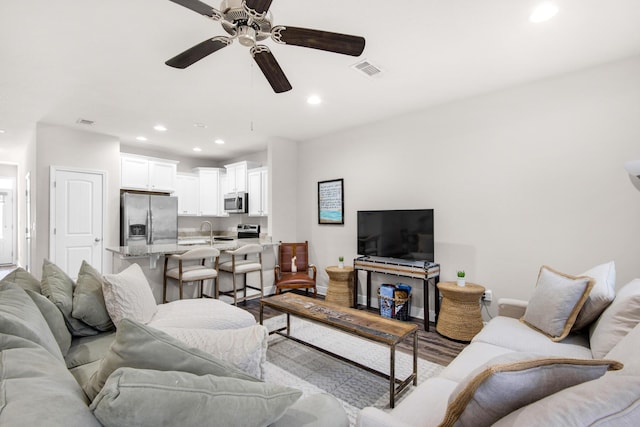 living room with ceiling fan, sink, and light hardwood / wood-style flooring