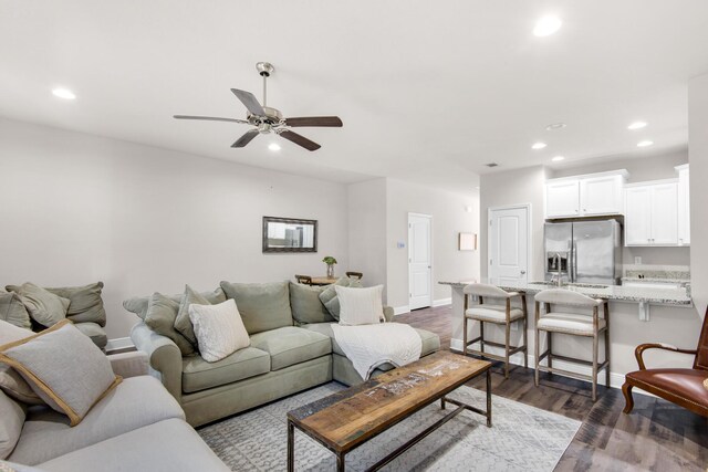 living room featuring ceiling fan and dark hardwood / wood-style flooring