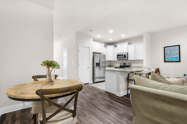 kitchen featuring white cabinetry, appliances with stainless steel finishes, light stone countertops, and dark hardwood / wood-style floors