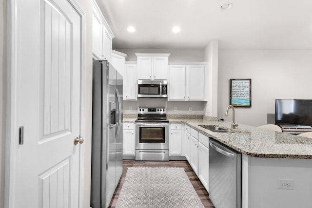 kitchen with white cabinetry, appliances with stainless steel finishes, sink, and kitchen peninsula