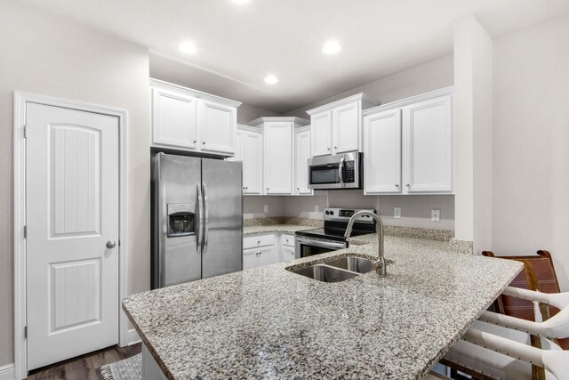 kitchen featuring dark hardwood / wood-style floors, kitchen peninsula, a breakfast bar, white cabinets, and appliances with stainless steel finishes