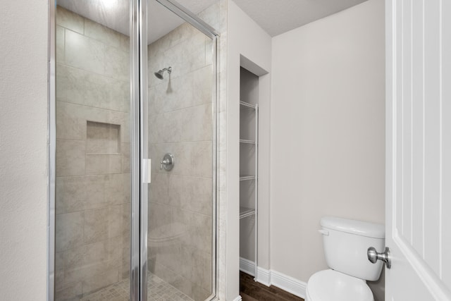 bathroom with wood-type flooring, toilet, and a shower with door