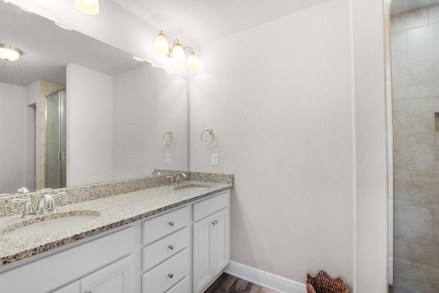 bathroom with hardwood / wood-style flooring, oversized vanity, and dual sinks