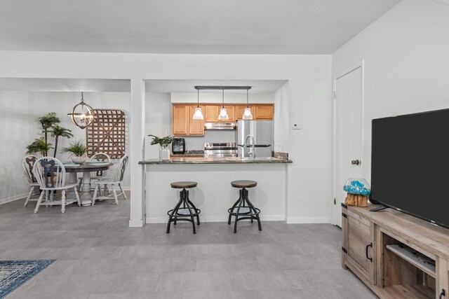 kitchen featuring hanging light fixtures, an inviting chandelier, kitchen peninsula, a breakfast bar area, and appliances with stainless steel finishes