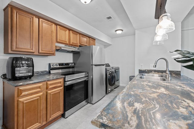 kitchen featuring sink, independent washer and dryer, dark stone countertops, pendant lighting, and appliances with stainless steel finishes