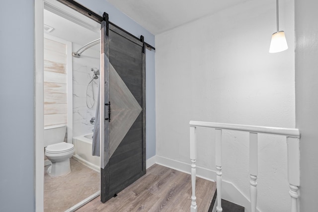 bathroom featuring hardwood / wood-style floors, tiled shower / bath combo, and toilet