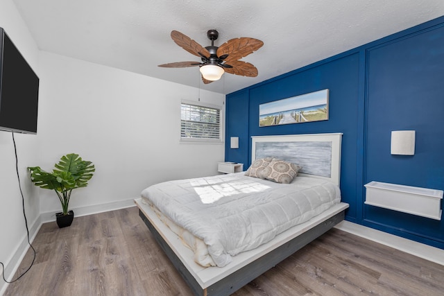 bedroom featuring hardwood / wood-style flooring, ceiling fan, and a textured ceiling