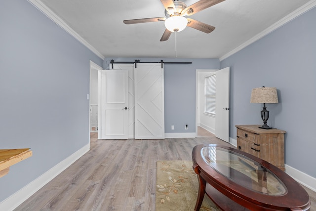 living area with a barn door, ceiling fan, light hardwood / wood-style floors, and ornamental molding