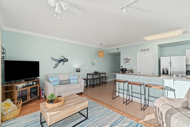 tiled living room featuring ceiling fan, crown molding, and rail lighting