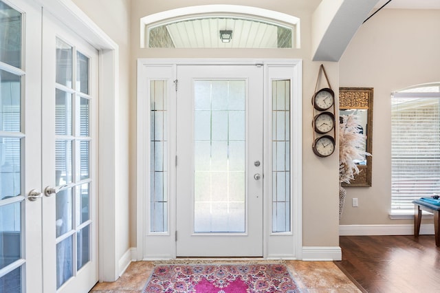 entrance foyer with arched walkways, french doors, baseboards, and wood finished floors