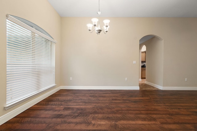 spare room featuring a chandelier and dark hardwood / wood-style floors