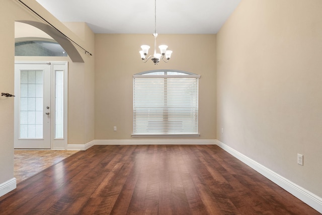 empty room with dark hardwood / wood-style flooring and an inviting chandelier