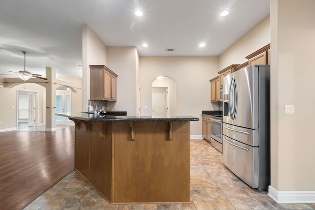 kitchen with kitchen peninsula, appliances with stainless steel finishes, a breakfast bar, and light hardwood / wood-style flooring