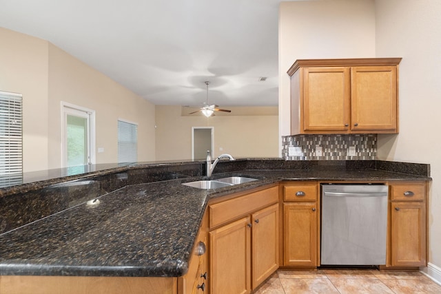 kitchen featuring stainless steel dishwasher, backsplash, dark stone countertops, and sink