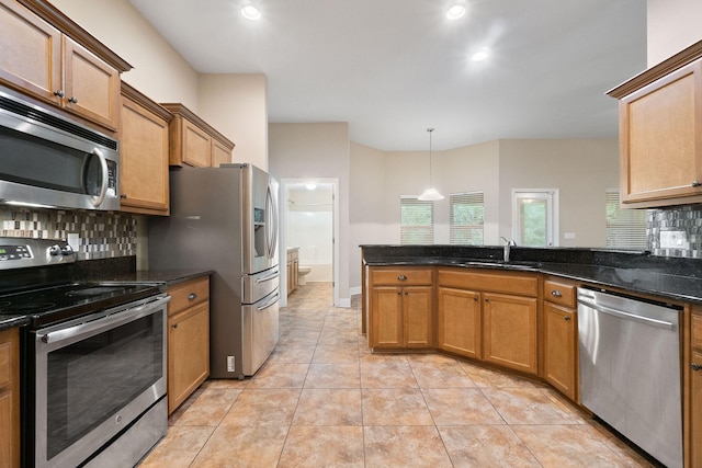 kitchen with sink, stainless steel appliances, tasteful backsplash, dark stone countertops, and pendant lighting