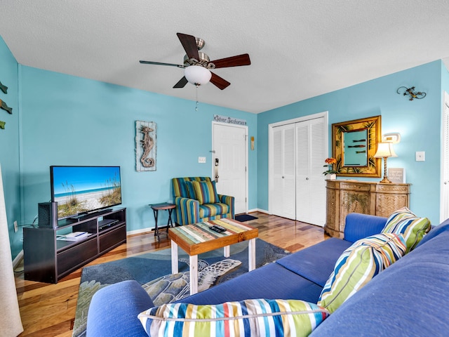 living room featuring ceiling fan, a textured ceiling, and hardwood / wood-style flooring